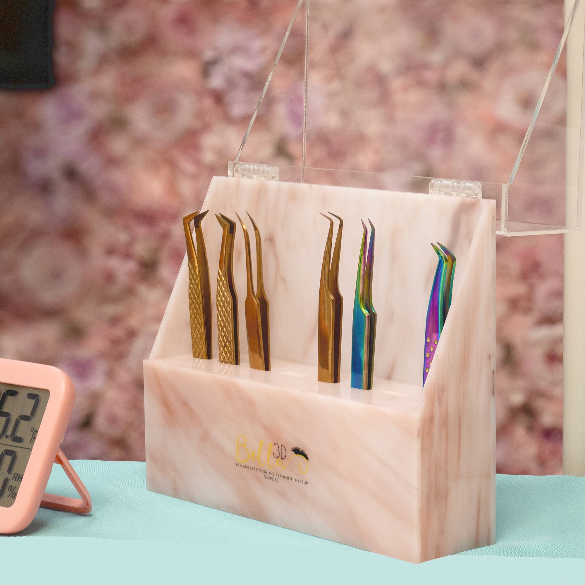 Acrylic Tweezer Stand holding six eyelash extension tweezers in metallic and rainbow finishes on a pink marble base.