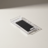 Clear plastic case of Cashmere Matte Easy Fan Lashes - 0.05 eyelash extensions arranged in rows on a light surface