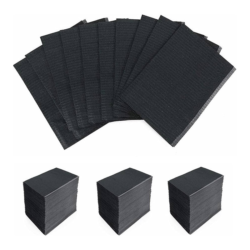 Black disposable Dental Bibs arranged fanned out and stacked in three neat piles on a white background