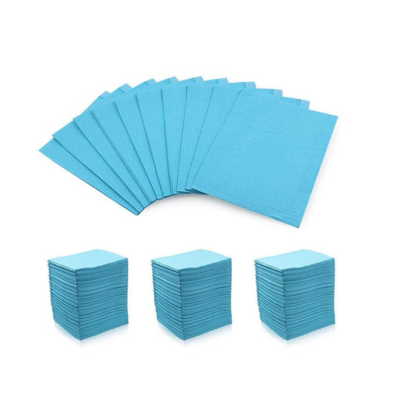 Blue disposable Dental Bibs neatly stacked in bundles and spread out on a white background for professional use