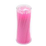 Disposable Micro Tip Applicators in bright pink, stored upright in a clear plastic container for eyelash extension supplies.