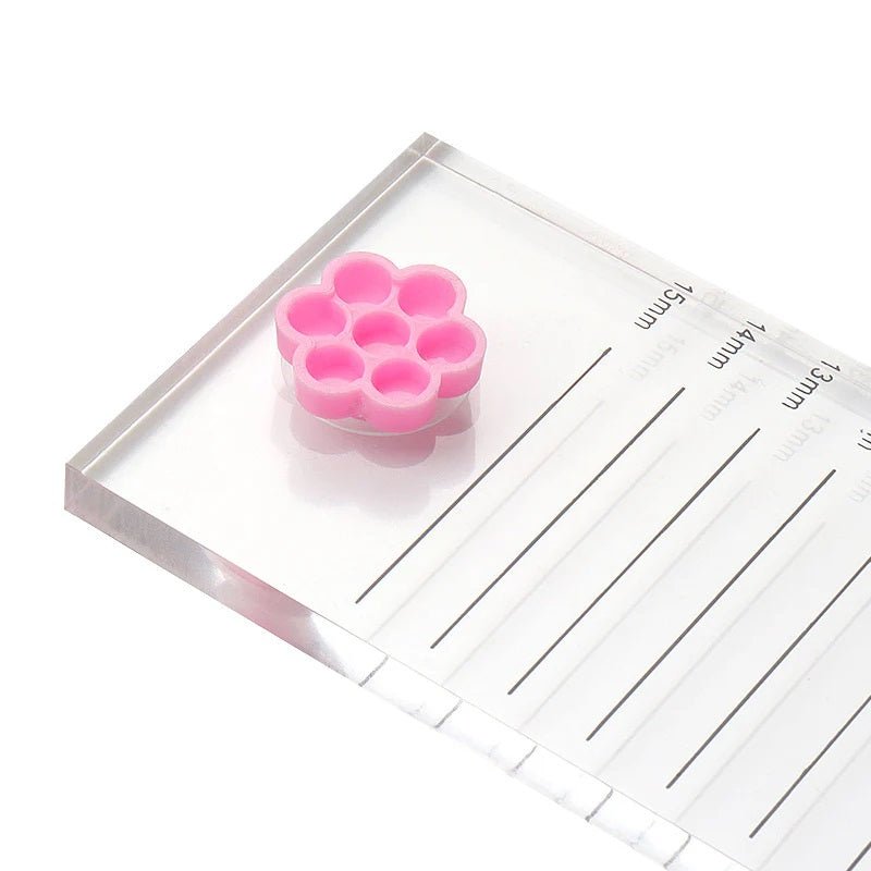 Pink honeycomb-shaped Honey Cups! Self-Adhering Glue Cups on a clear acrylic eyelash extension ruler