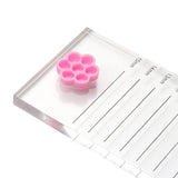 Pink honeycomb-shaped Honey Cups! Self-Adhering Glue Cups on a clear acrylic eyelash extension ruler