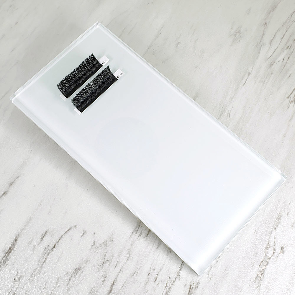 Clear rectangular Lash Glass Tiles on marble surface with two sets of black eyelash extensions