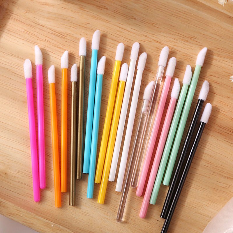 Colorful Lip Wands with angled white tips arranged on a wooden surface for precise cosmetic application