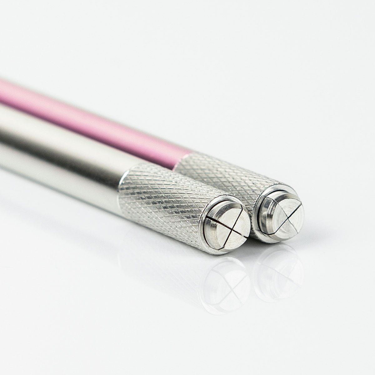 Close-up of two Manual Microblading Pen tools with metal grips and pink and silver handles on white background