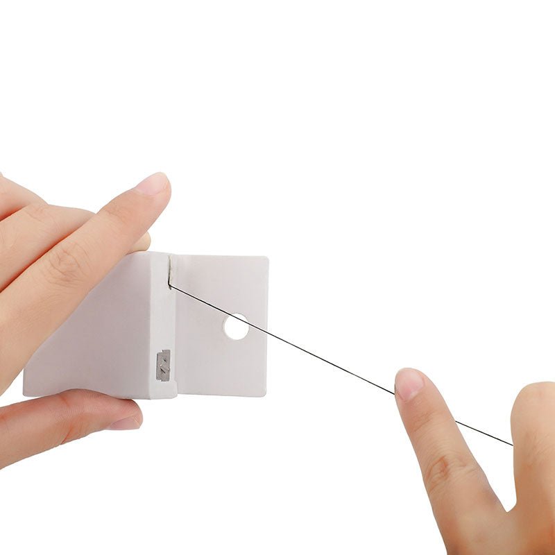 Hands holding and pulling thin black Pre-Inked Mapping String from a small white dispenser box on white background