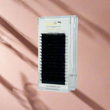 Signature Silk Collection - 0.05 black eyelash extensions in a transparent case with soft lighting shadows on a beige background