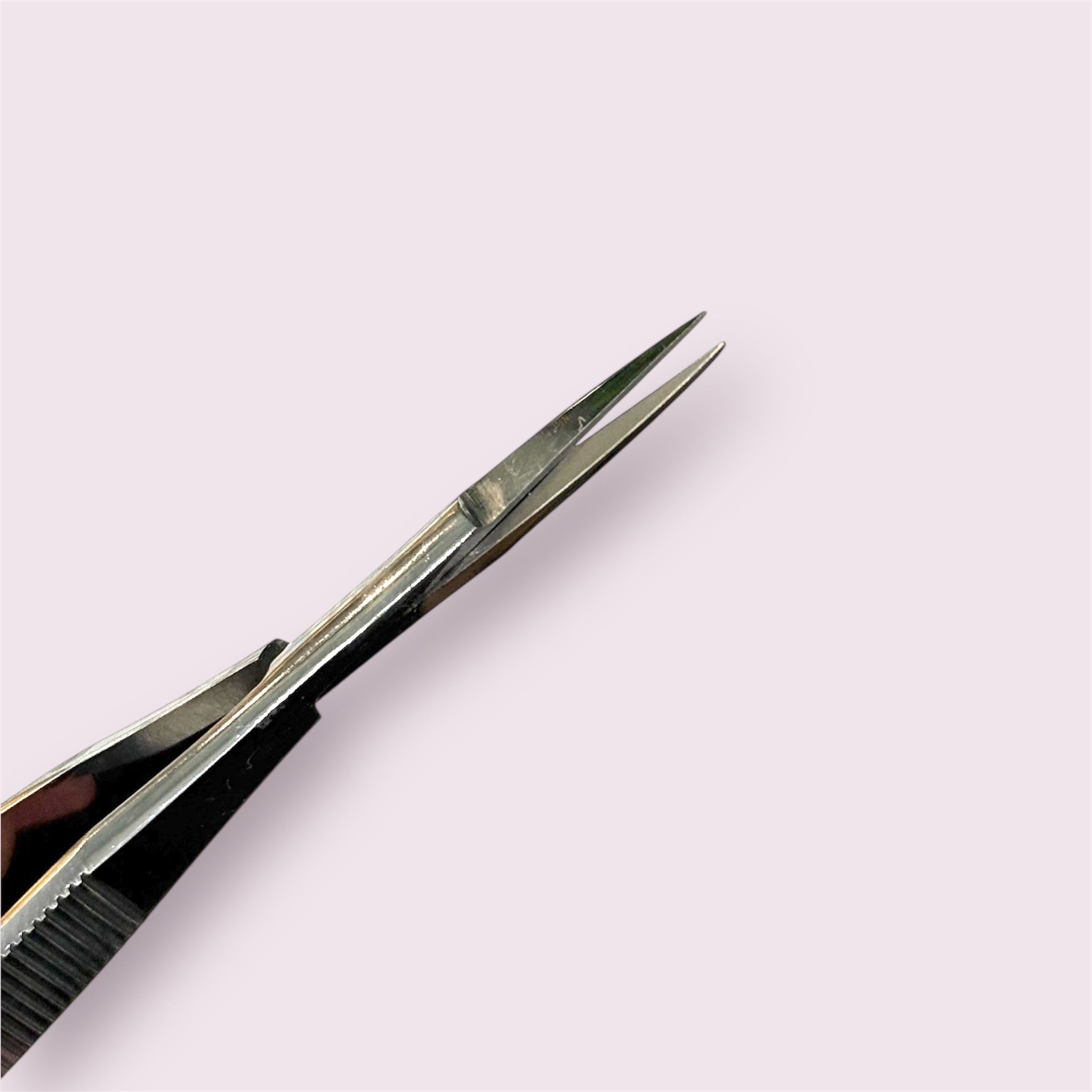 Close-up of stainless steel Straight Spring Scissors with pointed tips on a pale background