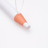 Close-up of the tip of a Tear And Pull Eyebrow Pencil with white and orange detailing on a white background