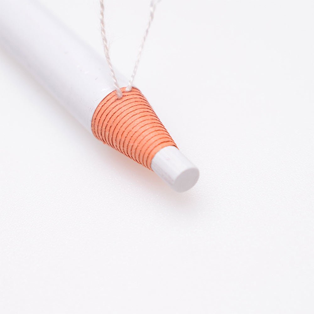 Close-up of the tip of a Tear And Pull Eyebrow Pencil with white and orange detailing on a white background