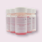 Clear bottles of Tweezer Cleansing Solution with pink liquid for cleaning eyelash extension accessories.
