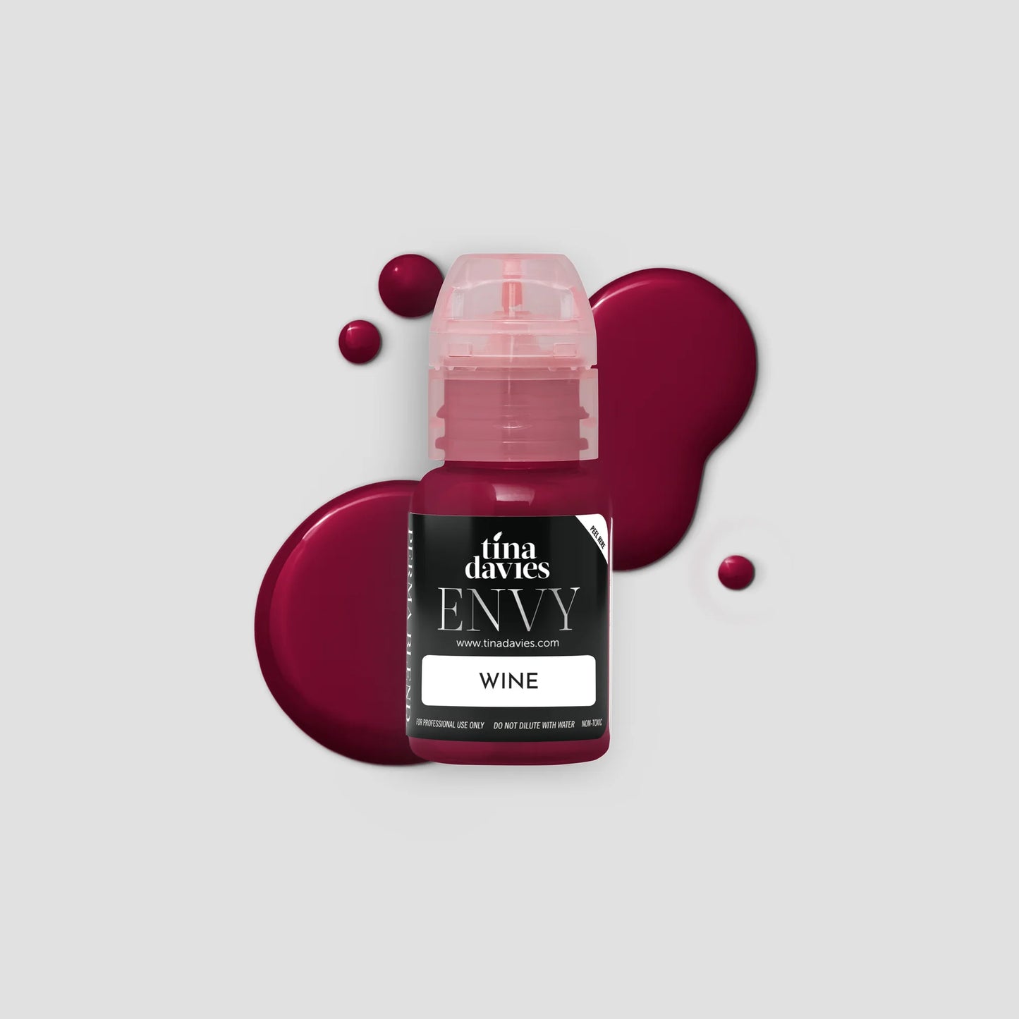 Bottle of Tina Davies Envy Wine with a splash of wine on a light gray background