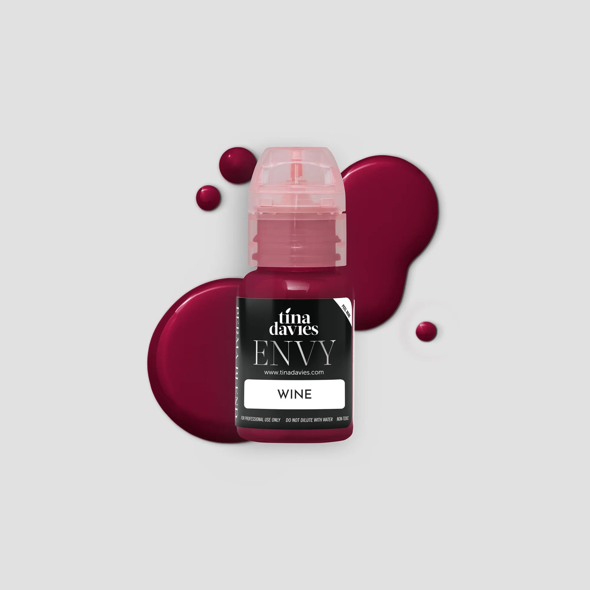 Bottle of Tina Davies Envy Wine with a splash of wine on a light gray background