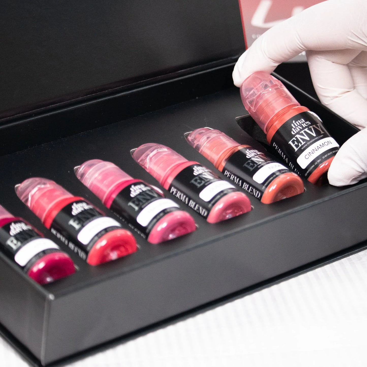 Set of Tina Davies Lip Pigments with a hand picking up a bottle to display