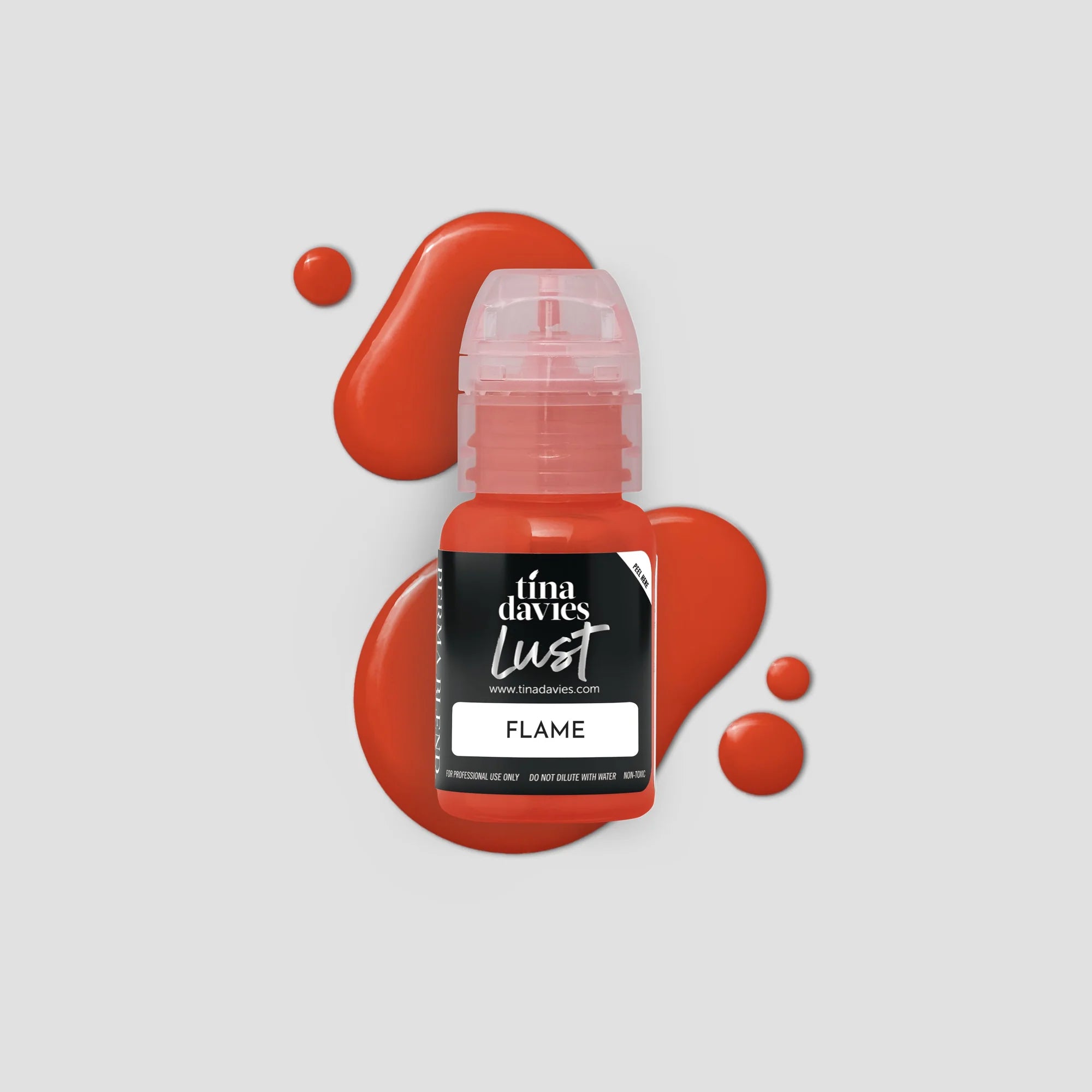 Bottle of Tina Davies Lust Flame lip pigment with red paint splashes on a light gray background
